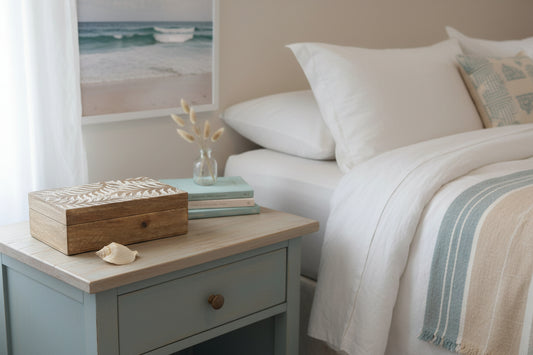 Wooden box with leaf pattern and a shell on a beige bedside table
